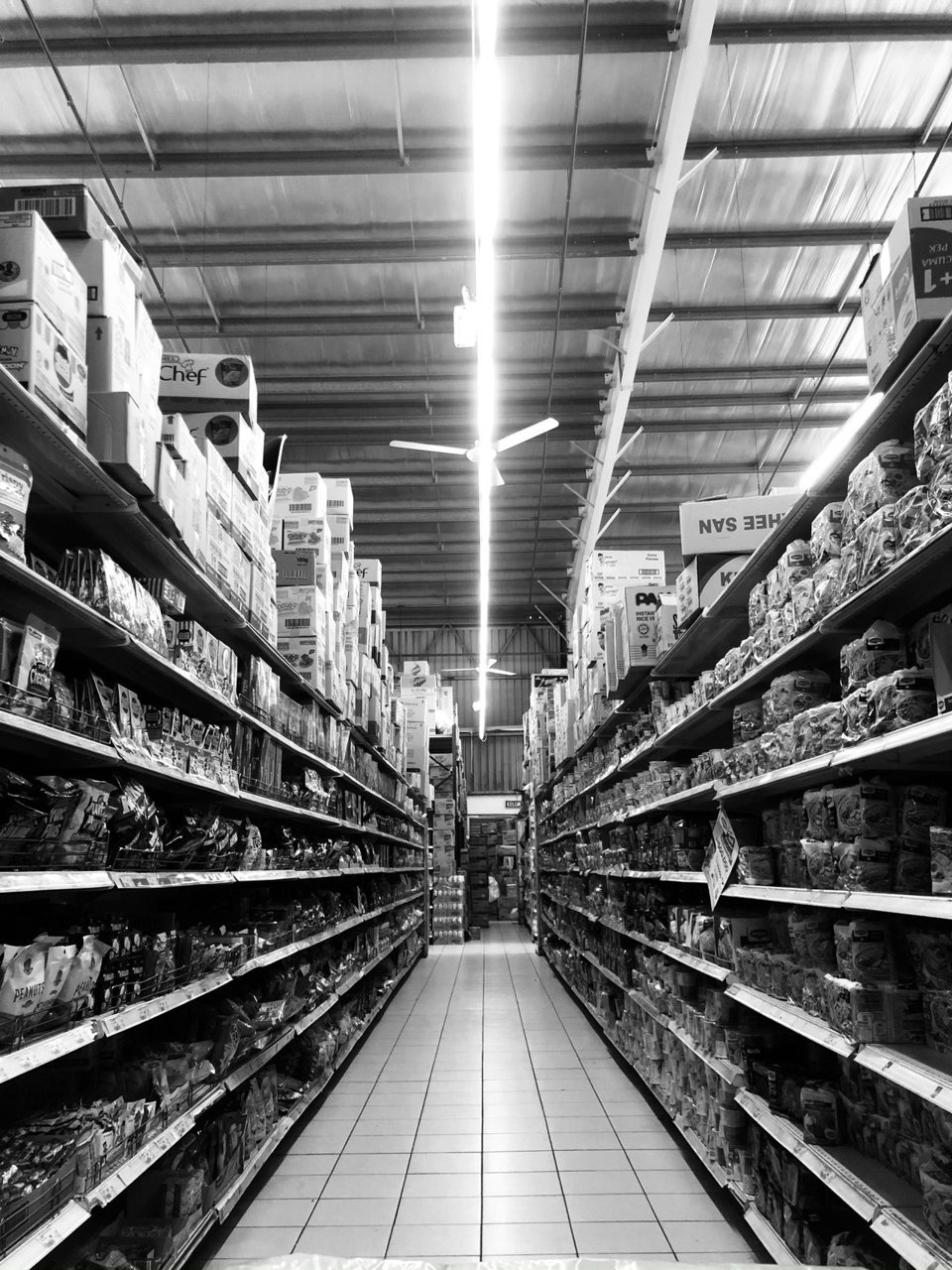 Free Black and white of shelves with different food and boxes placed in rows in shop with bright illumination Stock Photo